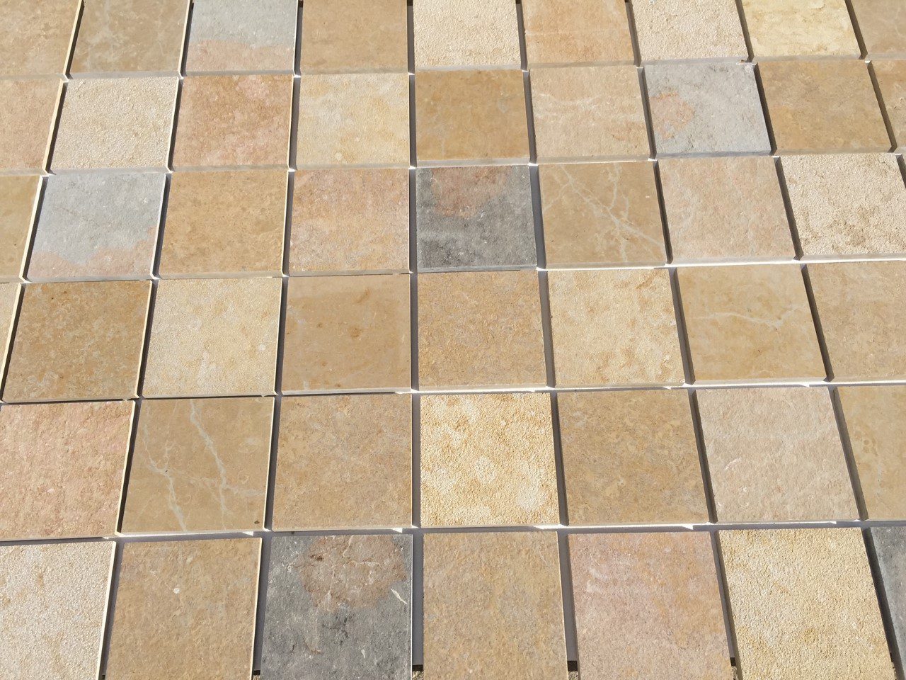 Close-up of a tiled surface with various beige and brown square tiles.