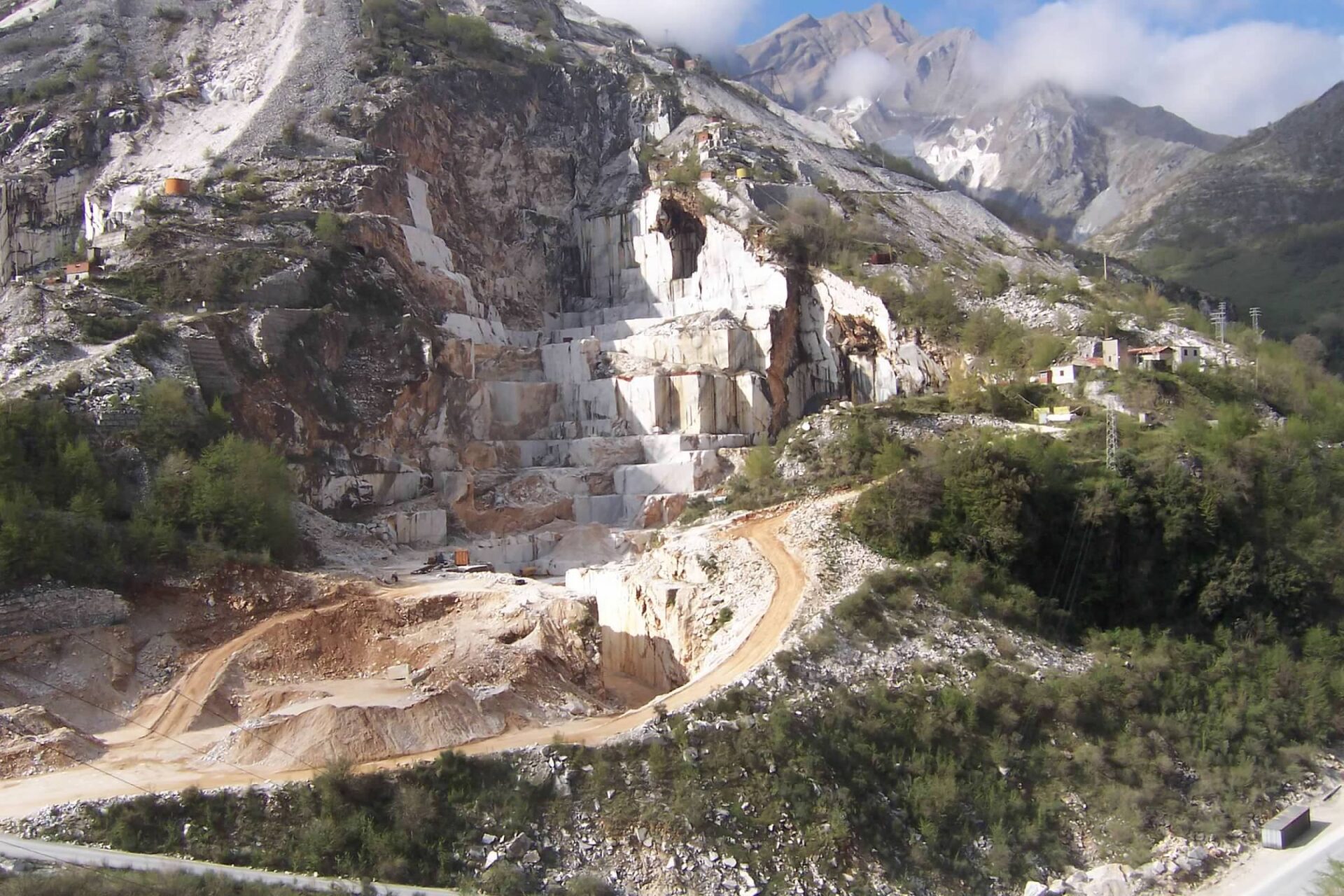 Quarry site with exposed rock formations and machinery tracks.